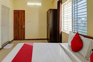 um quarto com uma cama com almofadas vermelhas e uma janela em OYO Flagship Sri Chamundeshwari Boarding And Lodge em Bangalore