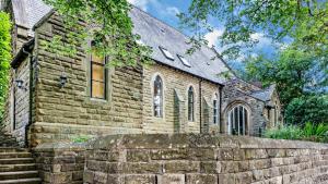 une ancienne église en pierre avec un mur en pierre devant dans l'établissement Chapel Retreat, à Buxton