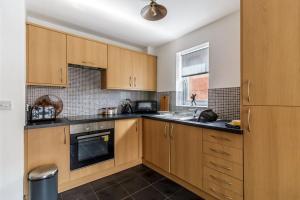 een keuken met houten kasten, een wastafel en een raam bij 2 Bedroom Flat, Glasshoughton in Castleford
