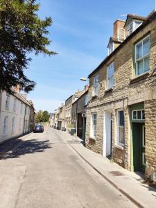 an empty street with buildings and a car on the road at Amarelo apartment, Central Charlbury, 1 Super king bed in Charlbury