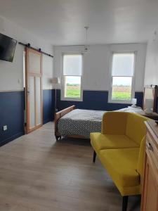 a bedroom with a bed and a yellow chair at Le Moole Veld in Steenbecque