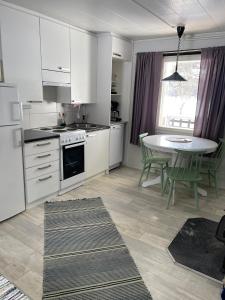 a kitchen with white cabinets and a table with chairs at Arctic Lodge Hetan Kota in Enontekiö