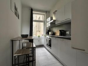 a kitchen with white cabinets and a table and a window at ***Stylische Wohnung direkt am Hauptbahnhof*** in Leipzig
