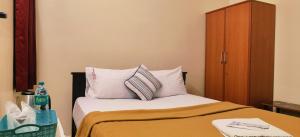 łóżko z białymi poduszkami i drewnianą szafką w obiekcie Black Pepper Cottage Yercaud w mieście Yercaud