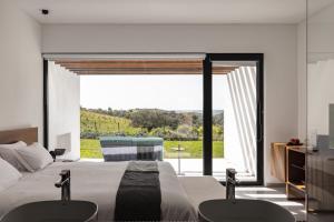 a bedroom with a bed with two chairs and a large window at Land of Alandroal in Évora