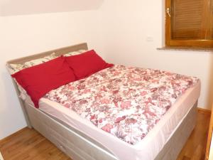 Cama en habitación con almohada roja en Vineyard cottage Mavrica, en Dragatuš