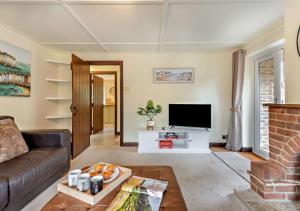 uma sala de estar com um sofá e uma televisão em Throop House Cottage - Bournemouth em Bournemouth