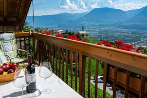 Una botella de vino sentada en una mesa en un balcón en Hof am Rain, en Cortaccia