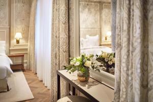 ウィーンにあるHotel Zur Wiener Staatsoperのベッドと花のテーブルが備わるホテルルームです。