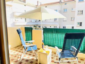 a balcony with two chairs and an umbrella at Appartement 2 chambres à 100 m de la plage in Fréjus