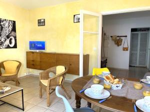 a living room with a table and chairs and a television at Appartement 2 chambres à 100 m de la plage in Fréjus