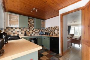 Modest 3 Bed Home, Normanton في نورمانتون: مطبخ مع دواليب خضراء وقمة كونتر