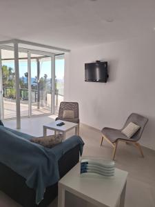 Apartamento en primera línea de mar de Salou في سالو: غرفة معيشة مع أريكة وتلفزيون على الحائط