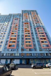 um edifício alto com carros estacionados num parque de estacionamento em Kvartirkoff na Bogatirskaya 6a, 3 floor em Kiev