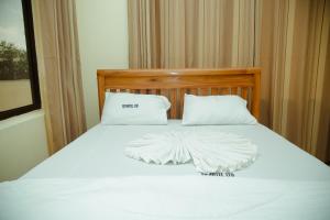 a bed with white sheets and pillows on it at FQ Hotel Limited in Dar es Salaam