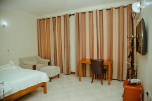 1 dormitorio con cama, escritorio y silla en FQ Hotel Limited, en Dar es Salaam