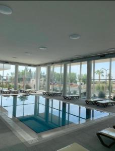 a swimming pool in a large building with chairs and windows at Sea view Penthouse ABELIA 12 floors iskele Cyprus in Iskele