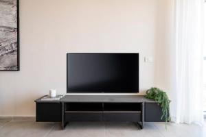 una TV a schermo piatto seduta sopra un centro di intrattenimento nero di Savyon View Tower - Isrentals a Gerusalemme