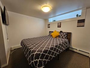 Schlafzimmer mit einem Bett mit einer schwarzen und weißen Bettdecke in der Unterkunft The MJ Tunnel Renovated Suite WiFi Parking in Moose Jaw