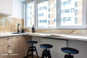 une cuisine avec deux tabourets à un comptoir et deux fenêtres dans l'établissement Central Residence Apartment 711 B2, à Vatra Mînăstirii Cotroceni