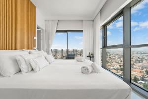 um quarto com uma grande cama branca e janelas grandes em Savyon View 3BDR - ApartHotels In City Center em Jerusalém