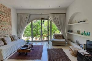 uma sala de estar com um sofá branco e uma grande janela em Cosy Studio in Mamilla, free parking up to 5 ppl em Jerusalém
