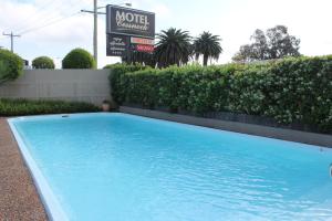 ein großer blauer Pool vor einem Motelschild in der Unterkunft Cessnock Motel in Cessnock