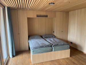 Cama en habitación pequeña con techo de madera en Tiny House Brunn am Gebirge en Brunn am Gebirge