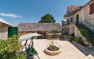 a patio with a green umbrella and some buildings at Holiday Home Marijeta in Škrip