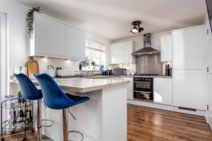 una cocina con armarios blancos y taburetes azules en 21 Ironfield Lane, en Prestwick