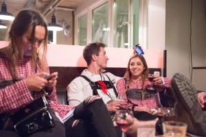 eine Gruppe von Menschen, die am Tisch sitzen und ihre Handys ansehen in der Unterkunft Wombat's City Hostel Munich Hauptbahnhof in München