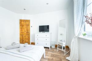 biała sypialnia z 2 łóżkami i telewizorem w obiekcie Charming 1-Bedroom Hideaway w mieście Kent