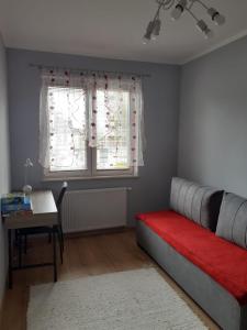 a bedroom with a bed and a desk and a window at Apartament Leśna 18 in Olsztyn
