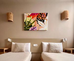 2 Betten in einem Zimmer mit Wandgemälde in der Unterkunft GM House Minorca in Cala'n Bosch