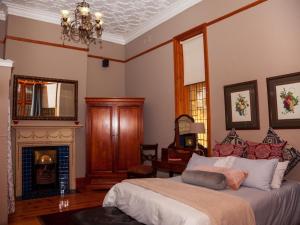 a bedroom with a bed and a fireplace at De Avond Rust in Oudtshoorn