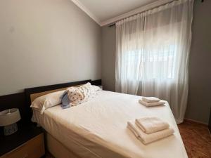 une chambre avec un lit blanc avec des serviettes dessus dans l'établissement BAJBAJ - Apartamento 2 dormitorios a 100 metros de la Playa del Bajondillo, a 300 metros del centro de Torremolinos, à Torremolinos