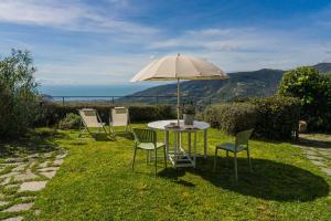 a table and chairs with an umbrella in the grass at Casale In Vigna, CinqueTerreCoast in Casarza Ligure