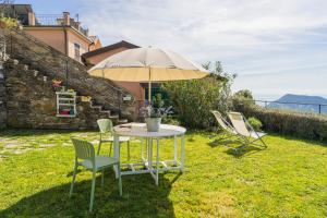 a table and chairs with an umbrella in the grass at Casale In Vigna, CinqueTerreCoast in Casarza Ligure