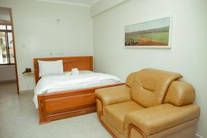 ein Schlafzimmer mit einem Bett und einem Stuhl in der Unterkunft FQ Hotel Limited in Daressalam