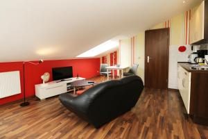 a living room with a black leather couch and red walls at QUARTIER 18 - Studio Sonnenschein 1 strandnah in Ostseebad Karlshagen