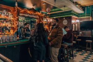 a group of people standing at a bar at PH Hostel Manchester NQ1 in Manchester