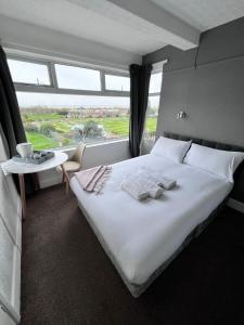 a bedroom with a large white bed with a large window at Harbour Hotel in Skegness