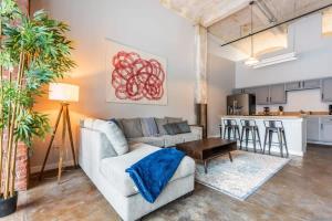 a living room with a couch and a kitchen at 3BR Luxury Historic Loft with Gym by ENVITAE in Kansas City