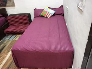a large purple bed with a pillow and a couch at Sequence Villa in Mumbai