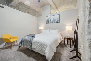 um quarto com uma cama branca e uma cadeira amarela em 3BR Luxury Historic Loft with Gym by ENVITAE em Kansas City