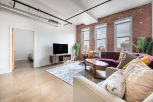 uma sala de estar com um sofá e uma televisão em 3BR 2BA Luxury Historic Loft With Gym by ENVITAE em Kansas City