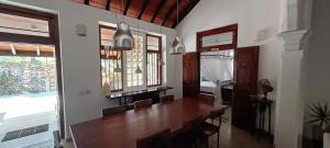 a dining room with a wooden table and windows at WG - Wathurugama in Gampaha