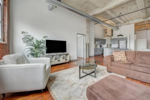 a living room with a couch and a tv at 2BR 2BA Spacious Historic Loft With Gym by ENVITAE in Kansas City