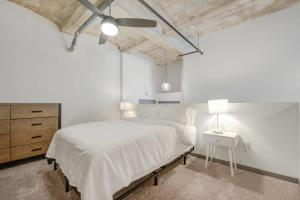 a white bedroom with a large bed and a dresser at 2BR 2BA Spacious Historic Loft With Gym by ENVITAE in Kansas City