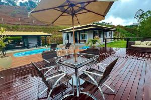 una mesa y sillas con una sombrilla en la cubierta en Casa de Campo completa nas montanhas capixabas en Marechal Floriano